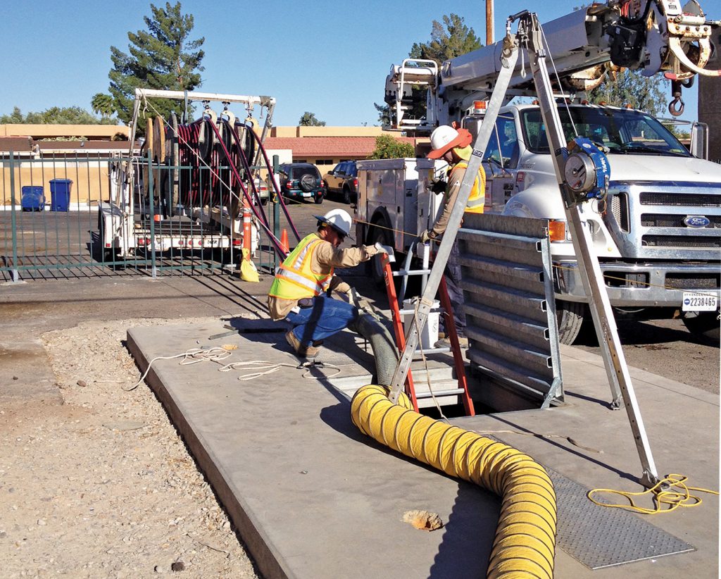Crews pull communication lines from a guideway manhole along the Central Mesa Extension.