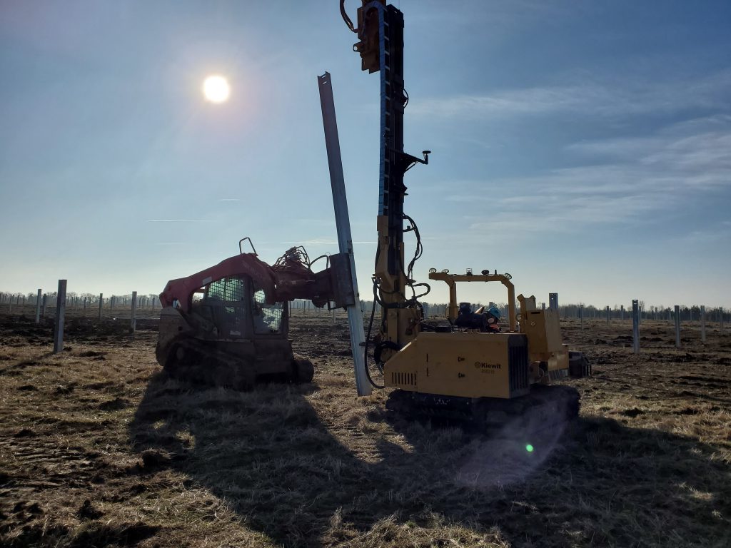 Two-man crews drive about 100 posts into the ground each day using this new grapple method. The 15 machines on site place around 1,500 posts daily.