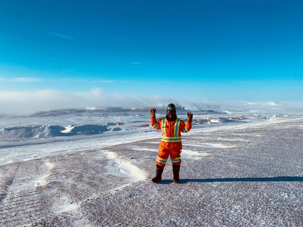A female construction worker poses in front of a frozen tundra