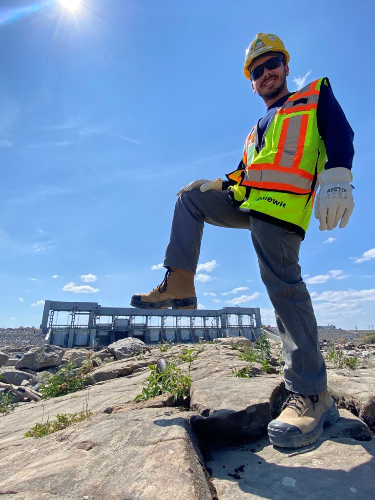 Image of a field engineer posing in front of a dam spillway