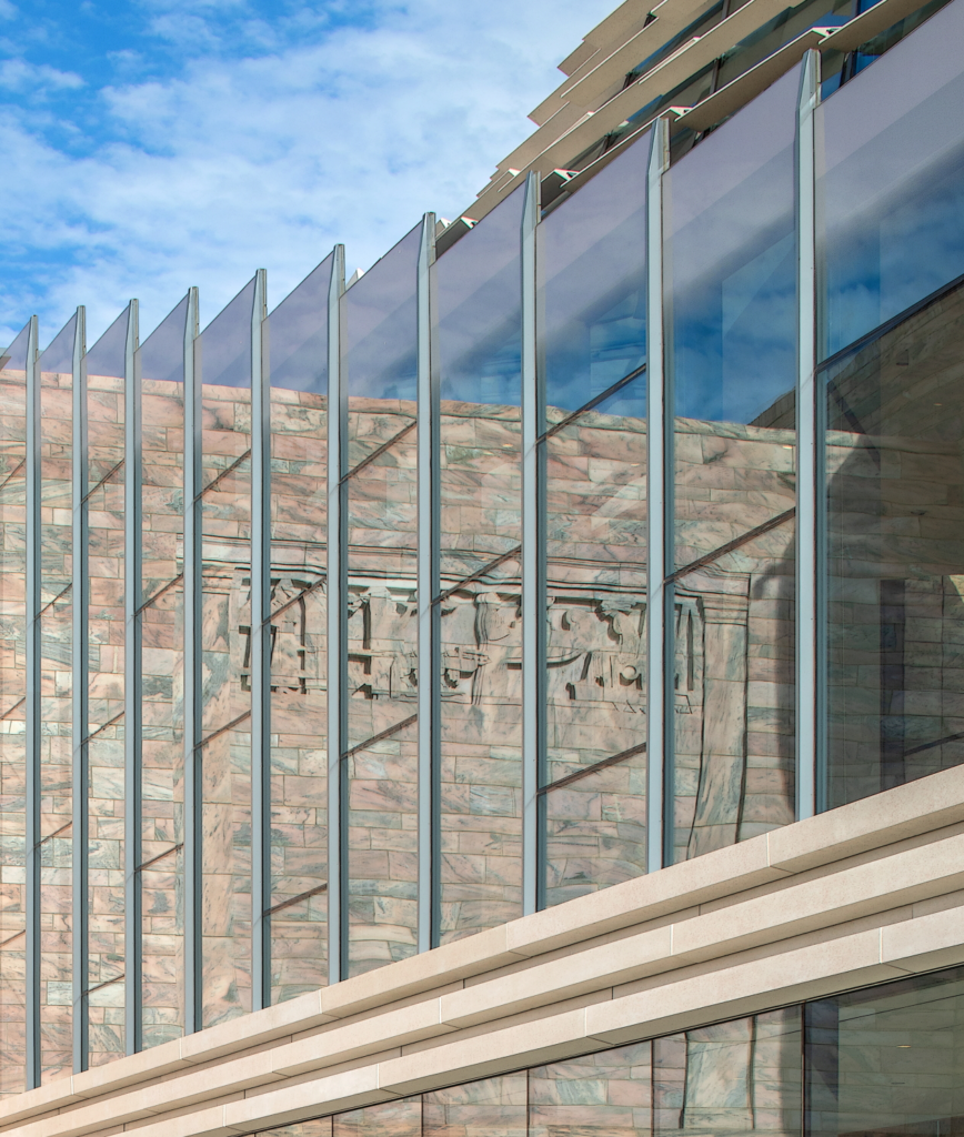 In this photo, the original museum can be seen as a reflection in the floor-to-ceiling glass walls of the new addition.